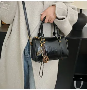 Dettaglio della borsa Boston nera lucida con cerniera dorata e ciondolo a forma di abaco