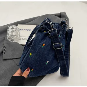 Détail de tulipes brodées sur un sac seau en denim bleu marine avec cordon de serrage