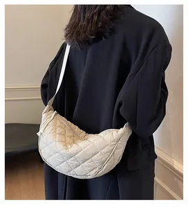 Close-up of beige quilted crescent bag with soft texture and wide shoulder strap