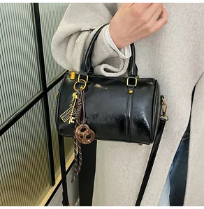 Dettaglio della borsa Boston in pelle nera lucida con hardware dorato e ciondoli chic