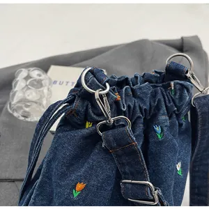 Gros plan sur la broderie de tulipes colorées d'un sac seau en denim bleu marine et métal argent