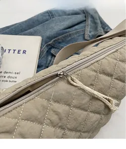 Detail of quilted khaki crossbody bag featuring a unique cream cotton rope knot zipper puller