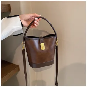 Detailed view of deep brown bucket bag with gold hardware and vintage texture