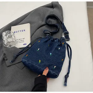 Détail de la broderie de tulipes sur un sac seau en toile bleu marine à cordon