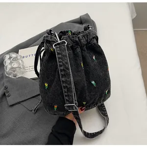 Détail de la broderie florale sur le sac seau en denim avec fermeture à cordon