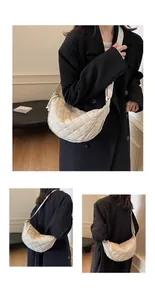 Detail view of cream quilted crescent crossbody bag with wide shoulder strap and zip closure