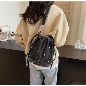 Détails de broderie florale sur sac seau en denim noir avec cordon de serrage
