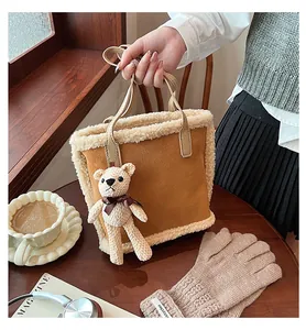 Detail of winter brown suede bucket bag with white fleece trim and cute bear charm