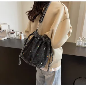 Détail de tulipe brodée sur un sac seau en denim avec large bandoulière réglable