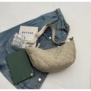 Detail of beige quilted crescent bag with adjustable wide strap on casual background