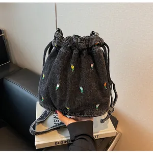 Détail de la broderie de tulipes sur un sac seau en denim noir avec motifs floraux