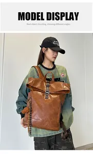 Detail view of large brown retro backpack with roll-top closure and metal buckle strap