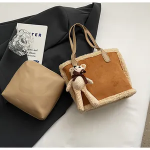 Flat lay of brown suede tote bag with faux shearling trim and mini pouch accessory