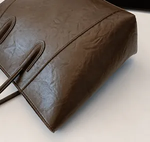 Detail shot of vintage dark brown faux leather tote bag showing oil wax texture and stitching