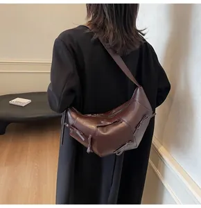 Détail d'un sac demi-lune marron foncé avec nœuds en relief porté par un mannequin chic