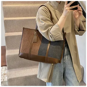 Detail der Kontrast-Tote-Bag mit strukturiertem Stoff, Lederbesatz und Metallfüßen