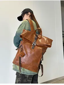 Rear view of a vintage brown leather backpack with roll-top closure on male model