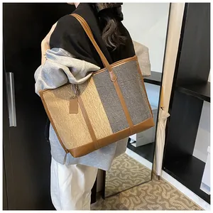 Makro-Detail der Color-Block-Tasche aus Denim mit braunen Ledergriffen und Anhänger