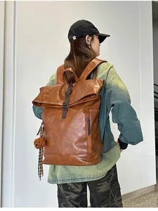 Close-up of brown PU leather backpack with vintage flap cover and cute plush bear pendant