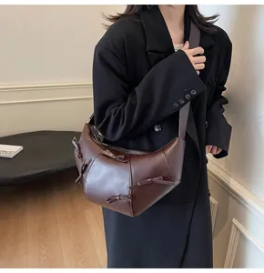 Gros plan d'un sac croissant marron foncé avec des nœuds décoratifs en cuir