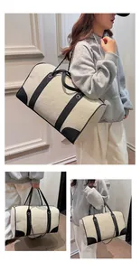 Detail of a large canvas tote with black leather trim and decorative silver chain