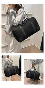Detail view of large black canvas travel bag featuring leather corners and metal chain strap