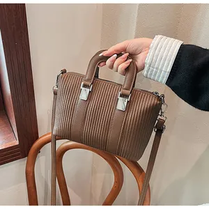 Detail of a brown lychee-grain leather tote bag with elegant vertical stripe embossing