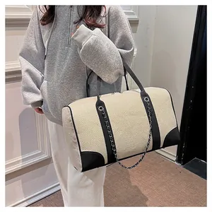 Close-up of contrast canvas travel bag with leather trim and silver metal chain detail