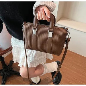 Detail of a brown tote bag featuring unique vertical pleated texture and silver hardware