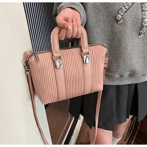 Detail of pink-orange textured crossbody bag with silver hardware and adjustable strap