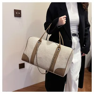 Detail of contrast canvas tote bag with leather straps and decorative metal chain detail