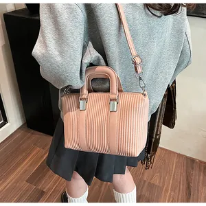 Detail of light pink pleated tote bag featuring vertical stripes and silver metal buckles
