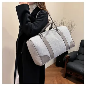 Detail of grey textured canvas handbag with leather trim and chain shoulder strap on model