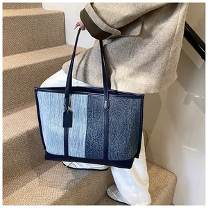 Detail einer großen Kontrast-Denim-Tote-Bag mit blauen Lederriemen auf einer Treppe