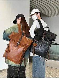 Detail of waterproof PU leather backpacks in black and brown with buckled roll-top closure