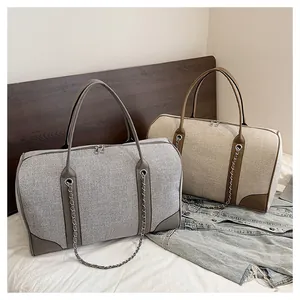 Detail of large canvas tote bags in grey and khaki with metal chains and leather accents