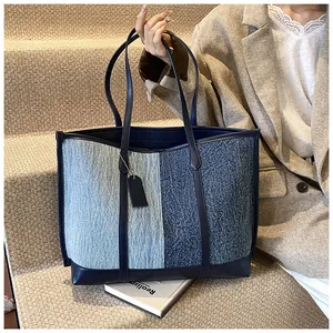 Detail der Kontrast-Denim-Tote-Bag mit blauem Ledergriff und Textur-Nahaufnahme