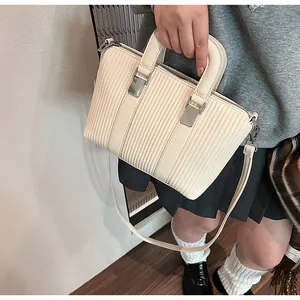 Detail of cream tote bag featuring vertical quilted texture and sleek silver hardware