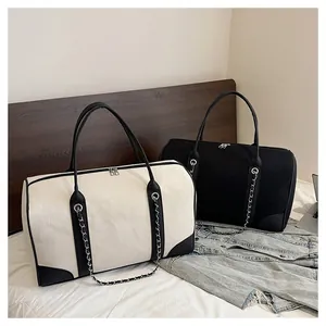 Detail of canvas tote bags with metal chain and leather reinforcement on a bed