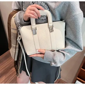 Detail of cream striped handbag with pleated texture and silver hardware on a model