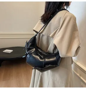 Détail du sac cabas en similicuir noir avec nœuds 3D porté avec un trench-coat classique