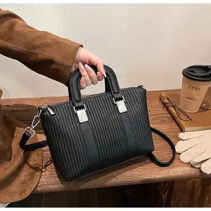 Close-up of black pleated tote bag with silver hardware on a cozy wooden table