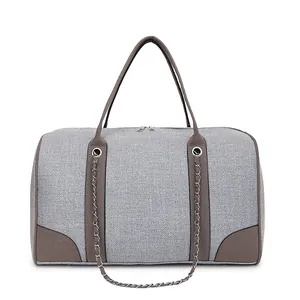 Detail of woven fabric canvas tote with leather corners and metal chain accents