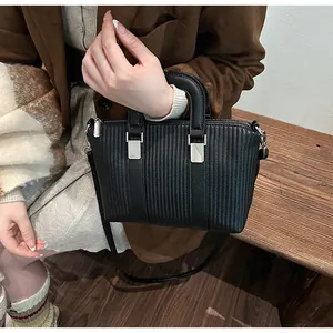 Macro view of black crossbody bag featuring vertical pleated texture and silver hardware