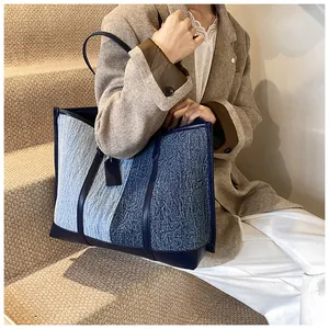 Detailansicht einer blau kontrastierenden Tragetasche kombiniert mit einem braunen Blazer