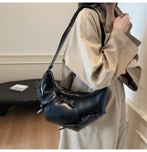 Détail du sac bandoulière demi-lune noir avec nœuds élégants et finition en cuir lisse