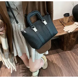 Detailed view of black pleated tote bag with silver hardware in a lifestyle setting
