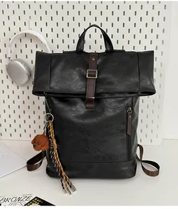 Detail of black PU leather backpack with rollover flap, brown straps and plush bear charm