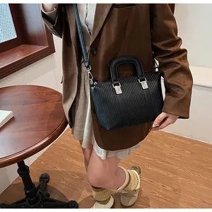 Close-up of black textured tote bag with silver hardware on a brown blazer outfit