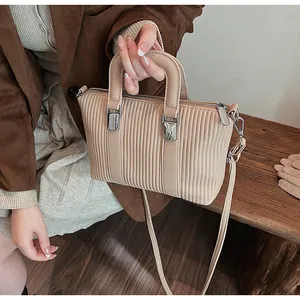 Detail of beige tote bag featuring vertical pleated texture and silver metal hardware
